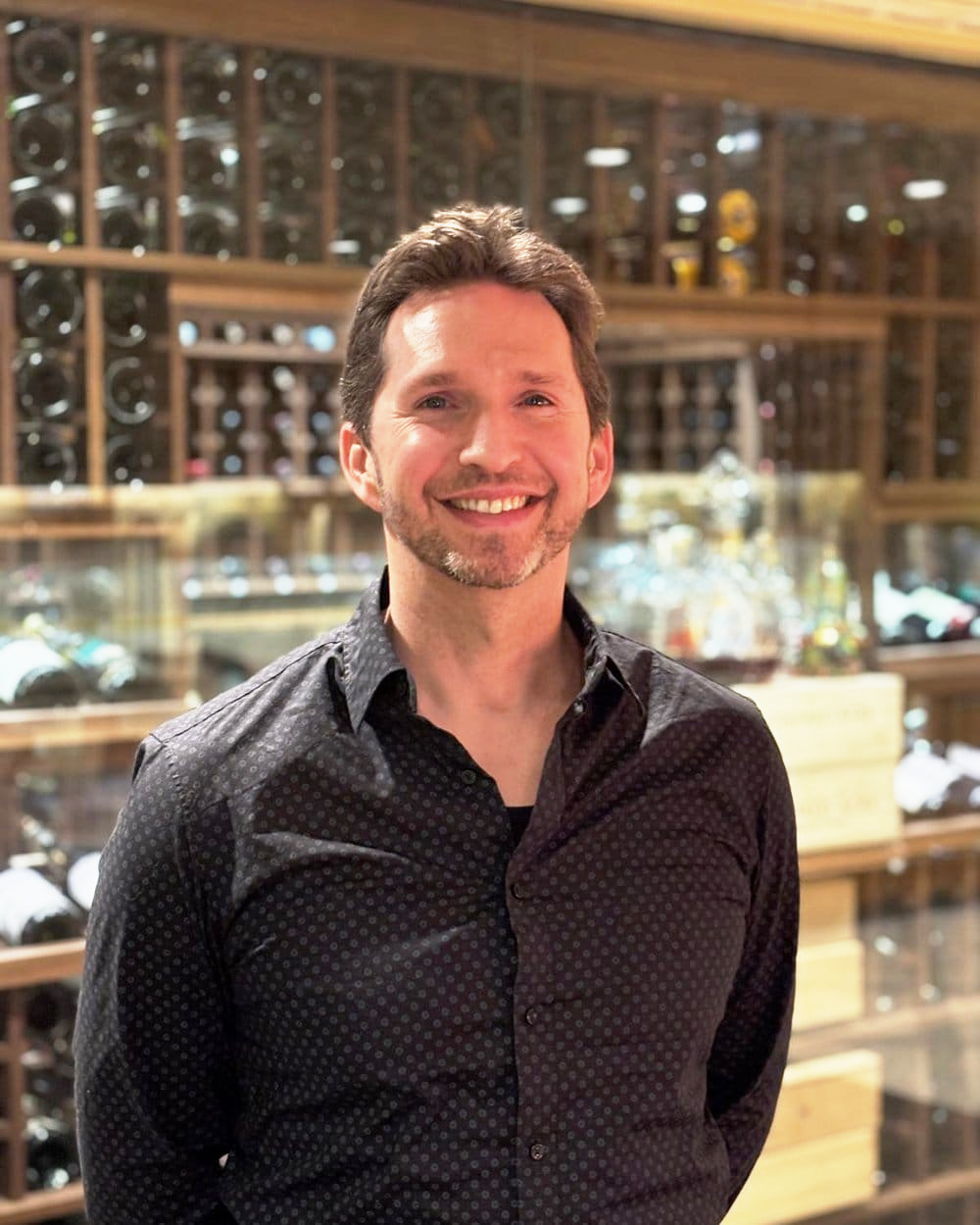 Noel Rosencranz smiling in a wine cellar
