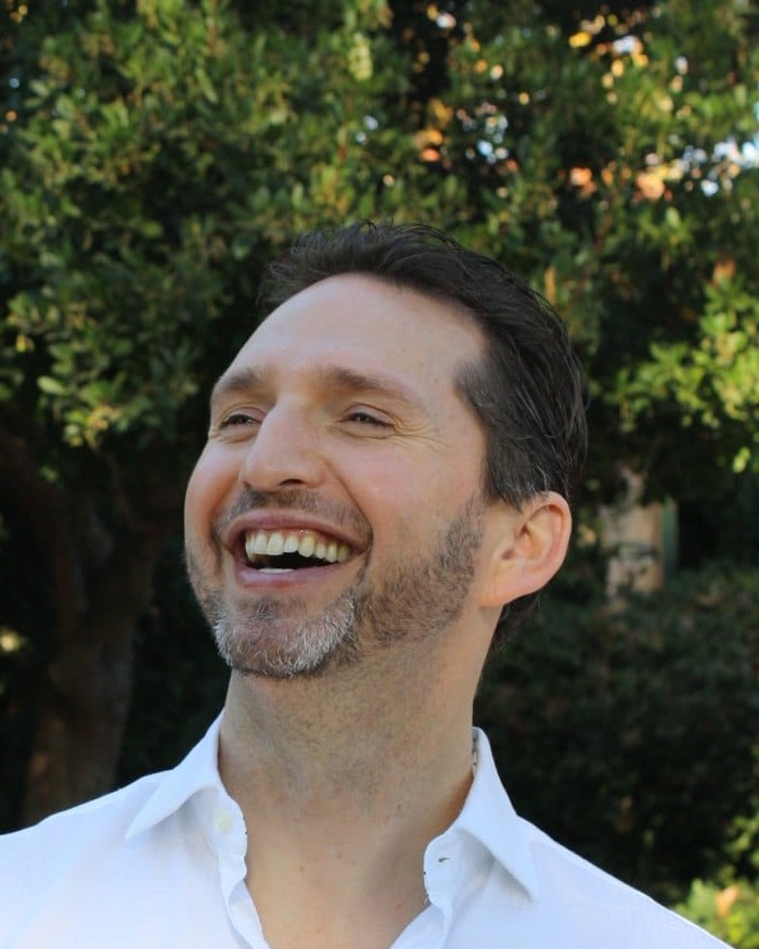 Noel outdoors, head back, laughing
